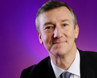 An image of a man wearing a suit and tie agains a plain purple background